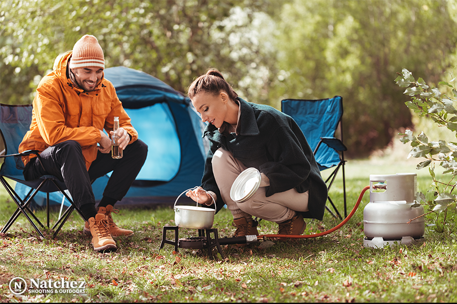 A happy camping couple cooking food in a pot?