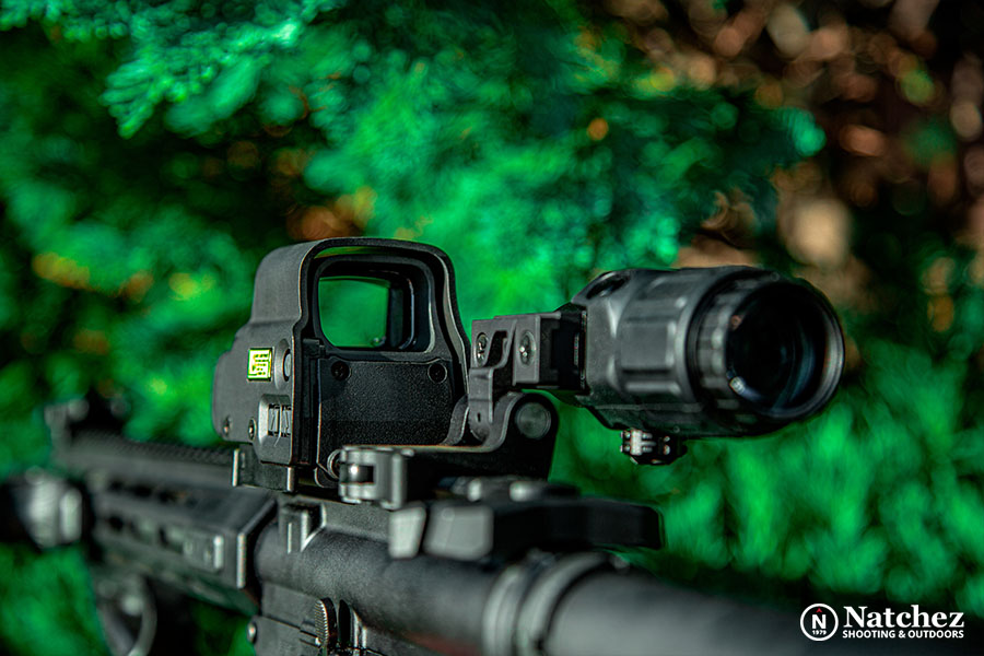 Green dot sight against foliage on tactical firearm