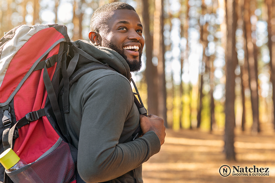 A young smiling man hiking in a forest