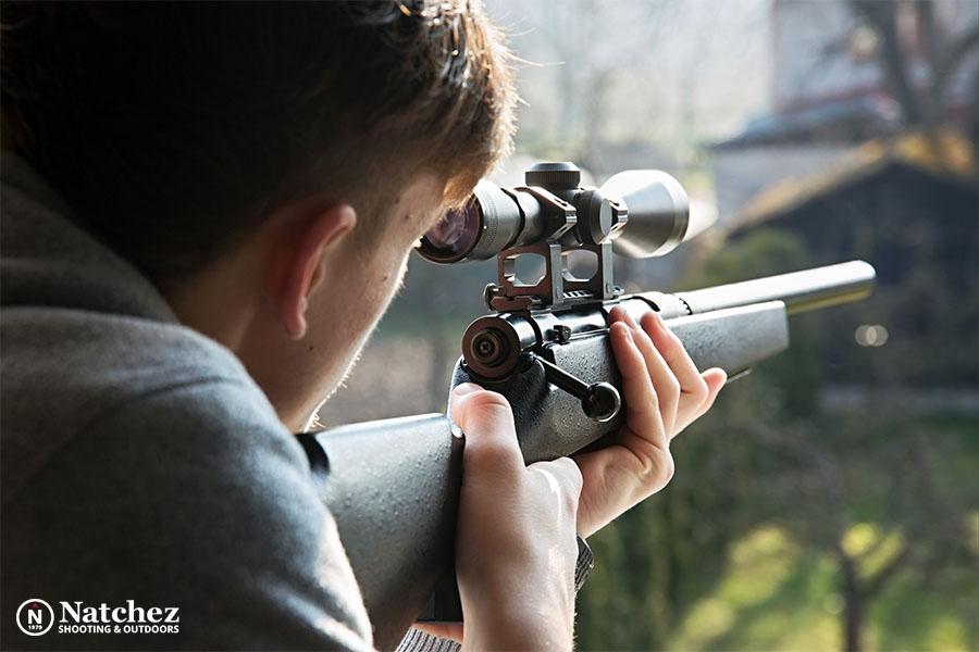 A young man using a rifle with a scope?