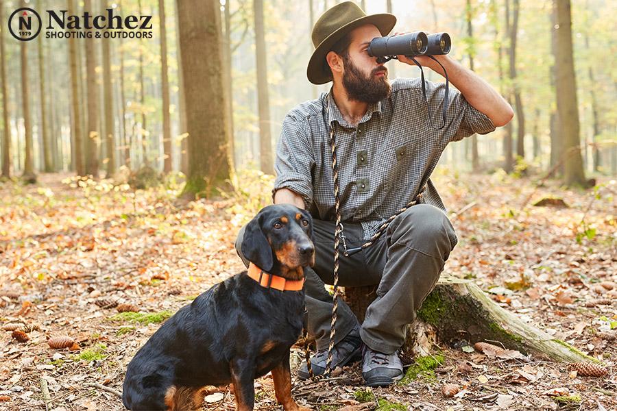 A man with a hunting dog looking through binoculars?